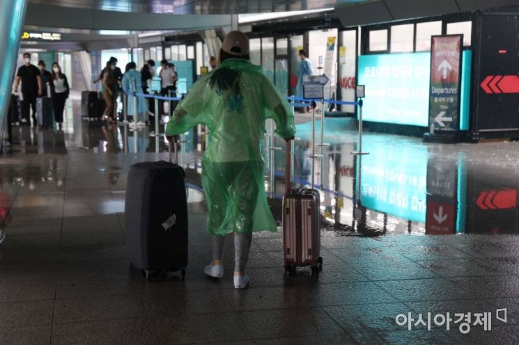 13일 인천국제공항 제1여객터미널에서 우비를 입은 해외 입국자가 코로나19 검사센터로 향하고 있다. /문호남 기자 munonam@