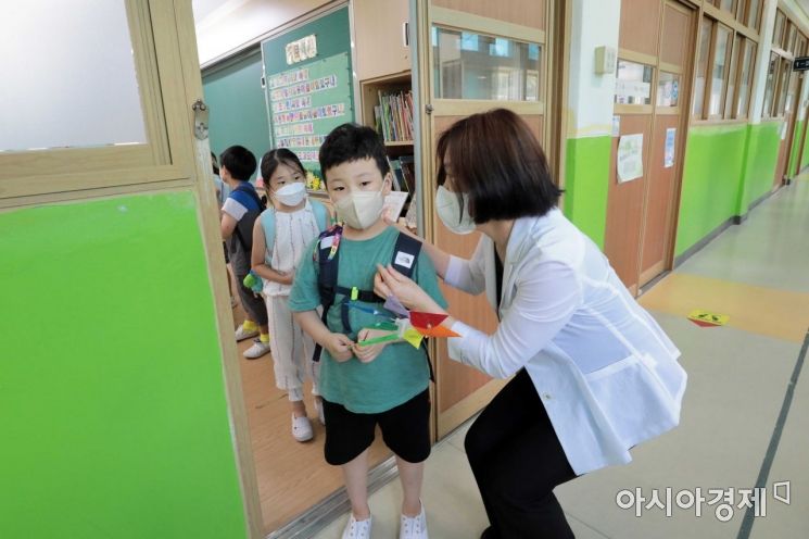 초등학교 여름 방학을 앞두고 지난 15일 서울의 한 초등학교에서 교사가 방학식을 마친 학생들에게 코로나19 예방을 당부하며 하교를 돕고 있다. /강진형 기자 aymsdream@