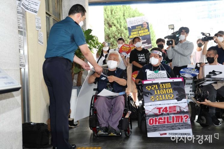 전국장애인차별철폐연대 회원들이 19일 서울 용산경찰서에 자진 출석하기 전 기자회견을 하며 경찰 관계자에게 입장문을 전달하고 있다. /문호남 기자 munonam@