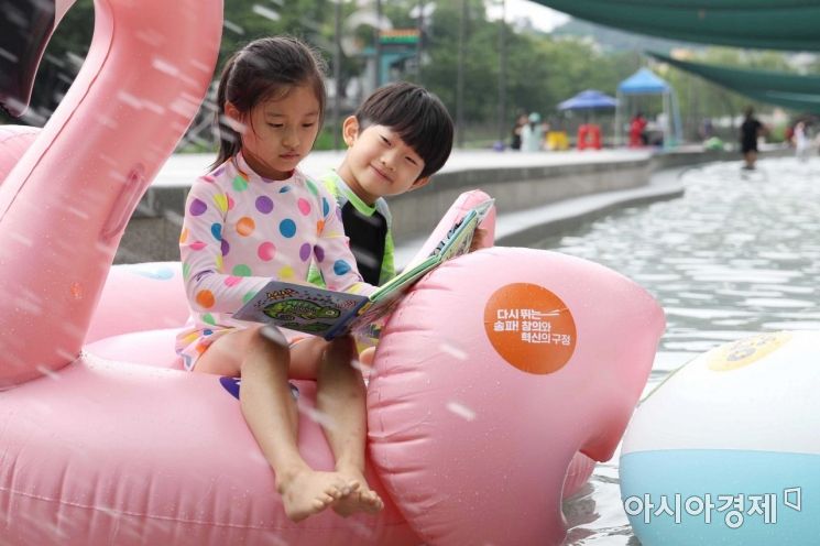 22일 서울 송파구 성내천 물놀이장에서 어린이들이 물놀이를 하며 책을 읽고 있다. /문호남 기자 munonam@