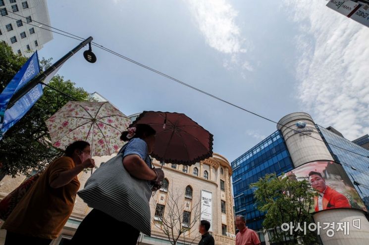 서울 한 낮 기온이 34도까지 상승하며 불볕더위가 이어지고 있는 28일 서울 중구 명동에서 시민들이 양산으로 햇볕을 가리고 있다./강진형 기자aymsdream@
