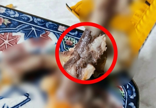 유명 치킨 업체에서 판매한 치킨 뼈에 검은 응어리들이 엉겨 붙어 있다. [이미지출처=연합뉴스]
