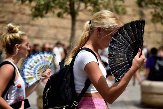 폭염이 이어지는 스페인 남부 세비야 거리에서 여성들이 부채질을 하며 걸어가고 있다. [이미지출처=연합뉴스]