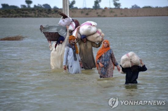 파키스탄 남서부 발루치스탄주 자프라바드에서 한 이재민 가족이 가재도구 등을 짊어지고 폭우로 침수된 지역을 지나고 있다.  사진=AP 연합뉴스