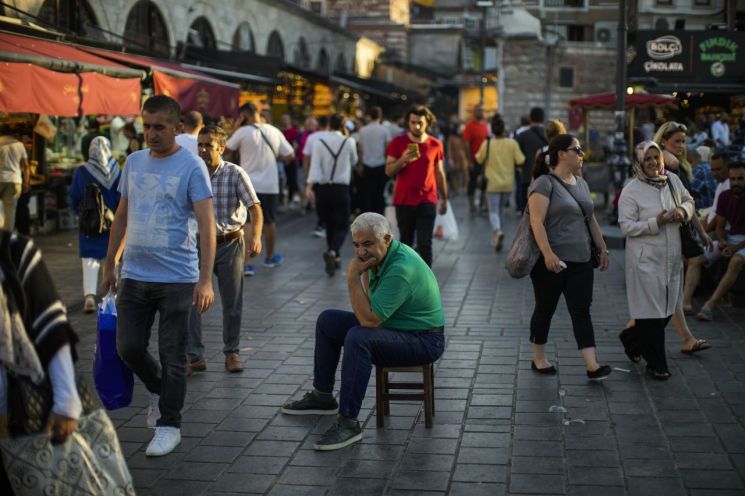지난달 18일(현지시간) 튀르키예(터키) 이스탄불의 한 이집트 향신료 시장에서 사람들이 오가는 가운데 한 남성이 의자에 앉아 있다. [이미지출처=연합뉴스]