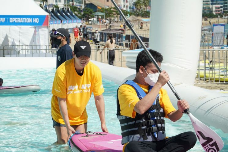 국립부경대학교 대외홍보대사 ‘블루’ 학생이 시각장애인을 위한 SUP 체험행사를 진행 중이다.