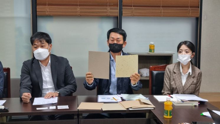 이창용 월자제지 대표(가운데)가 감귤박을 재활용해 제조한 골판지용 원지(오른쪽 밝은 종이)의 장점에 대해 설명하고 있다. 이 대표 왼쪽이 김영훈 일해 대표. [사진=중소기업 옴부즈만 출입기자단]