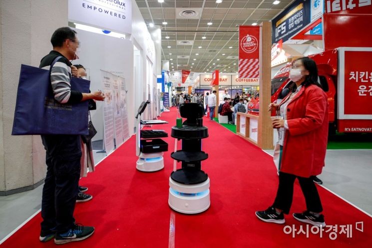 지난해 10월 서울 강남구 코엑스에서 열린 'IFS 프랜차이즈 서울'에서 관람객들이 서빙로봇을 보고 있다.