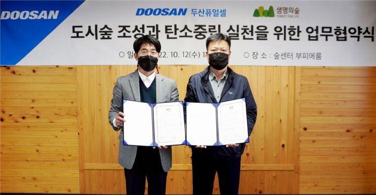 지난 12일 서울 마포구 숲센터에서 열린 ‘도시숲 조성과 탄소중립 실천’을 위한 업무협약식에서 박준영 두산퓨얼셀 전무(왼쪽)가 유영민 생명의숲 사무처장과 기념사진을 촬영하고 있다. 사진제공=두산퓨얼셀