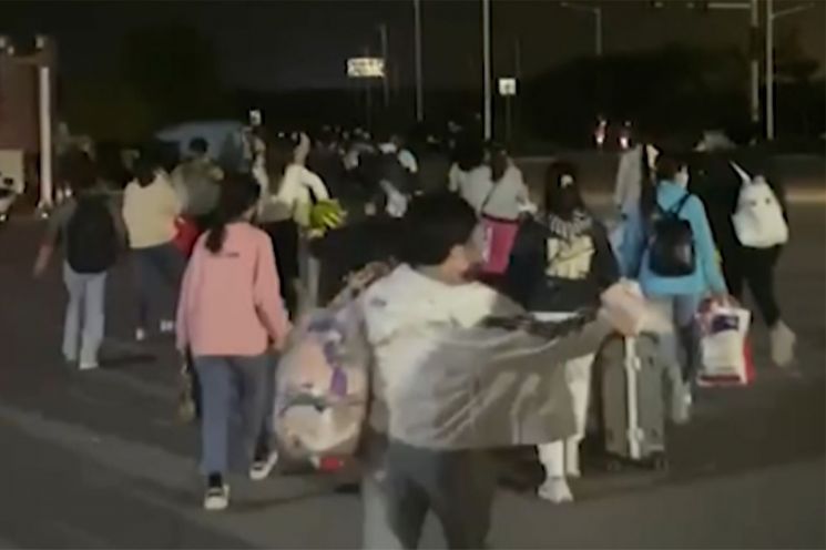 중국 허난성 정저우에 있는 폭스콘 공장 노동자들이 짐을 들고 공장을 떠나고 있다. [이미지출처=AP연합뉴스]