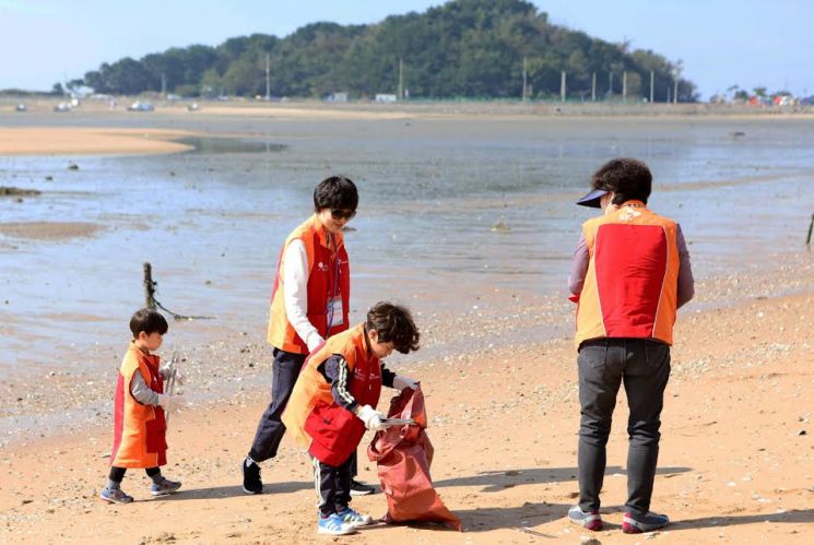 SK케미칼과 SK바이오사이언스, SK플라즈마 3사 구성원과 가족들이 인천 중구 을왕리 해변가에서 쓰레기를 줍는 '비치코밍' 봉사활동을 진행하고 있다. (사진제공=SK케미칼)
