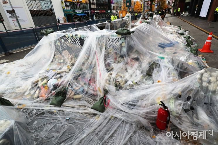 13일 서울 용산구 이태원역 1번 출구 인근에 시민들이 두고 간 국화꽃과 추모 메세지가 대형 비닐로 덮여 있다./윤동주 기자 doso7@