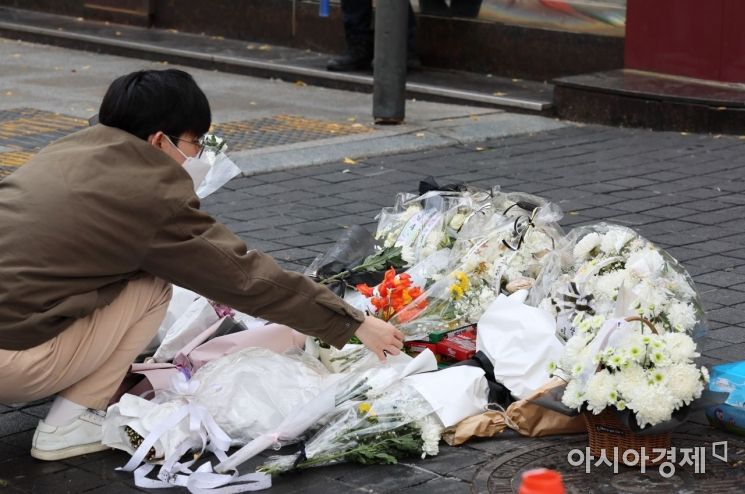 13일 서울 용산구 이태원 참사 현장 앞 인도에서 한 자원봉사자가 시민들이 두고 간 국화꽃과 추모 메세지를 정리하고 있다./윤동주 기자 doso7@