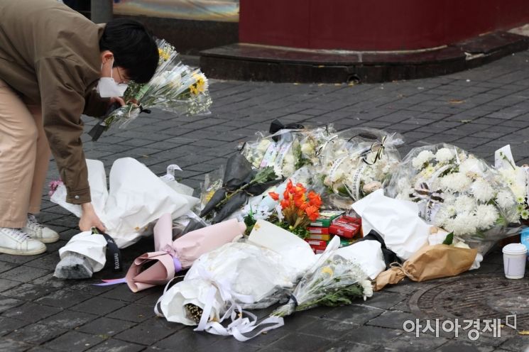 13일 서울 용산구 이태원 참사 현장 앞 인도에서 한 자원봉사자가 시민들이 두고 간 국화꽃과 추모 메세지를 정리하고 있다./윤동주 기자 doso7@