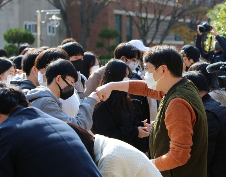 수험표를 나눠주는 경남 창원용호고등학교 교사가 수능을 앞둔 학생과 주먹악수를 하고 있다. / 이세령 기자 ryeong@
