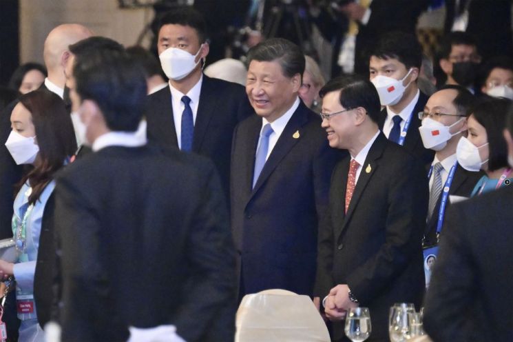 지난 17일(현지시간) 태국 방콕 APEC 정상회의 환영 만찬에서 시진핑 중국 국가주석(가운데)와 존 리 홍콩 행정장관이 마스크를 쓰지 않은 채로 대화를 나누고 있다. [이미지출처=AP연합뉴스]