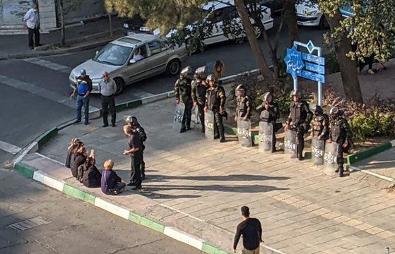 지난 10월 이란 여성들이 테헤란의 한 광장에서 히잡 쓰지 않고 보안군 맞은 편에 앉아 있는 모습으로 알려진 사진. 사진=AFP연합뉴스