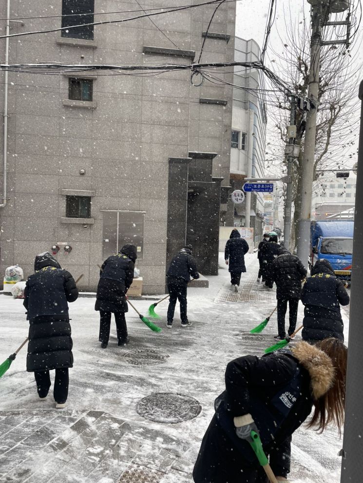 성북구 보문로 일대에서 제설차량이 작업 중인 가운데 삼선동주민센터 직원들이 도보에 쌓인 눈을 치우고 있다.