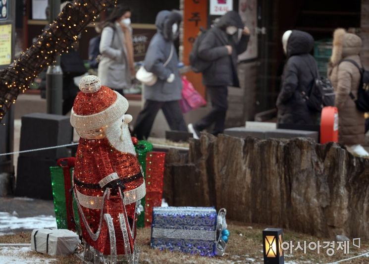 올 들어 가장 추운 영하의 날씨가 계속되는 가운데 성탄절을 앞둔 23일 서울 명동의 한 호텔 정원에 설치해 놓은 산타 인형 앞으로 두꺼운 옷으로 차려 입은 시민들과 관광객들이 지나가고 있다. /허영한 기자 younghan@