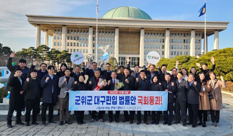 국회가 경북 군위군의 대구시 편입 법률안을 통과시킨 8일 김진열 군위군수와 관계자들이 국회 앞에서 기념촬영을 하고 있다. [이미지출처=연합뉴스]