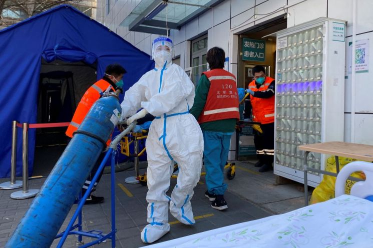 지난해 12월 23일 중국 베이징의 한 발열진료소에서 간호사가 산소탱크를 실어나르고 있다. ＜사진=로이터연합＞