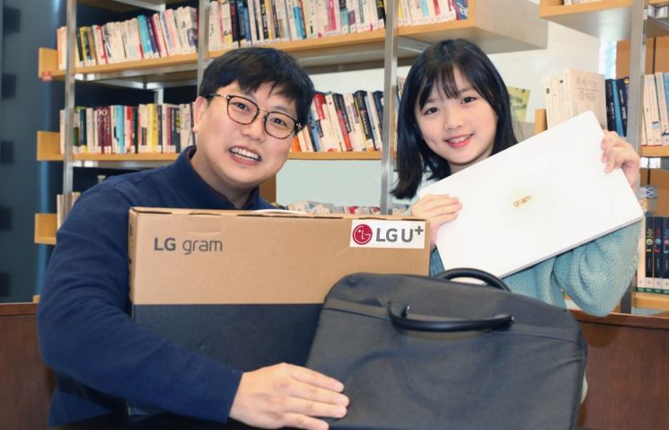 LG유플러스 임직원이 초등학교 입학을 앞둔 아동과 선물 받은 노트북을 소개하는 모습. 사진=LG유플러스