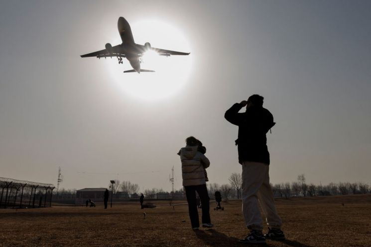 6일 중국 베이징 국제공항에서 사람들이 착륙 중인 비행기를 바라보고 있다. [이미지출처=로이터연합뉴스]