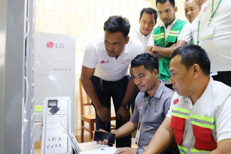 LG전자가 지난 10일 진행한 캄보디아 프놈펜 센속 LG-KOICA 희망직업훈련학교 가전 서비스 기술 특강 모습. 희망직업훈련학교 교사들이 에어컨 제품 수리 방법에 대해 엔지니어 설명을 듣고 있다.[사진제공=LG전자]