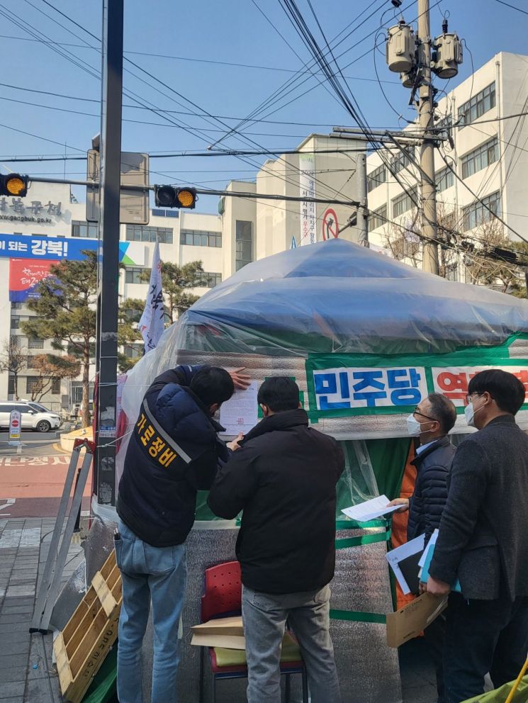 강북구 관계자들이 계고장을 불법천막에 부착하고 있다.