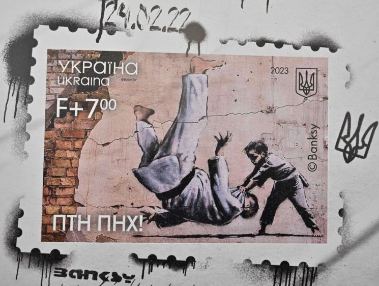 러시아의 우크라이나 침공으로 전쟁이 일어난 지 1년이 된 지난 24일(현지시간) 우크라이나가 뱅크시의 '푸틴 업어치기' 벽화로 기념우표를 발행했다. [사진출처=AFP 연합뉴스]