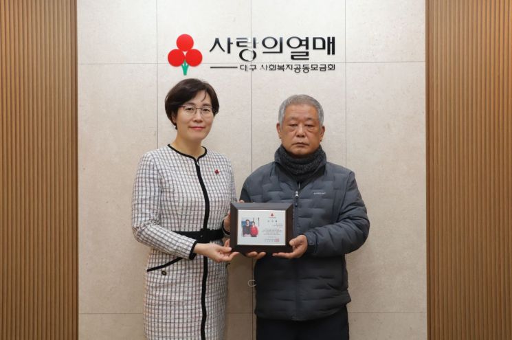 손전헌(오른쪽) 씨가 강주현 대구공동모금회 사무처장과함께 감사패를 들어보이고 있다.