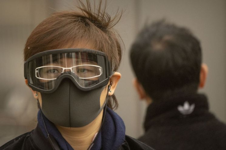 22일 중국 베이징 중심가에서 마스크를 쓰고 고글을 쓴 한 여성이 거리를 걷고 있다. [이미지출처=AP연합뉴스]