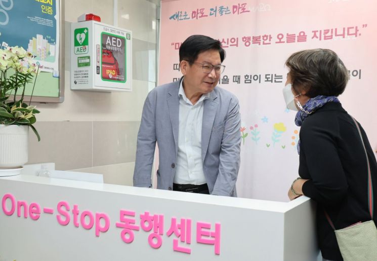 박강수 마포구청장(왼쪽)이 구청 6층에 조성된 ‘원스톱 동행센터’의 통합민원안내데스크에서 방문 주민과 이야기 나누고 있다.