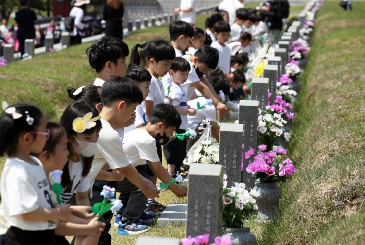 5·18 민주화운동 43주년을 이틀 앞둔 16일 광주 북구 운정동 국립 5·18민주묘지에서 아이들이 헌화하고 있다. 사진제공=연합뉴스