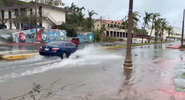 시속 241㎞의 돌풍을 동반한 '슈퍼 태풍' 마와르가 태평양의 미국령 괌을 강타한 25일(현지시간) 한 자동차가 투몬 만의 침수된 거리를 지나가고 있다. [이미지출처=AFP연합뉴스]