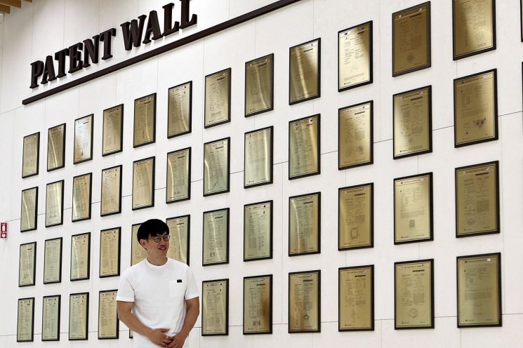 '올해의 발명왕' 이성국 책임연구원이 LG이노텍 본사에 있는 특허의 벽 앞에서 사진촬영을 하고 있다. 2019년 조성된 특허의 벽은 발명자의 자긍심 고취와 발명에 대한 동기 부여를 목적으로 하고 있다. 특허 50건을 게시하기 시작해 매년 업데이트 중이다.
