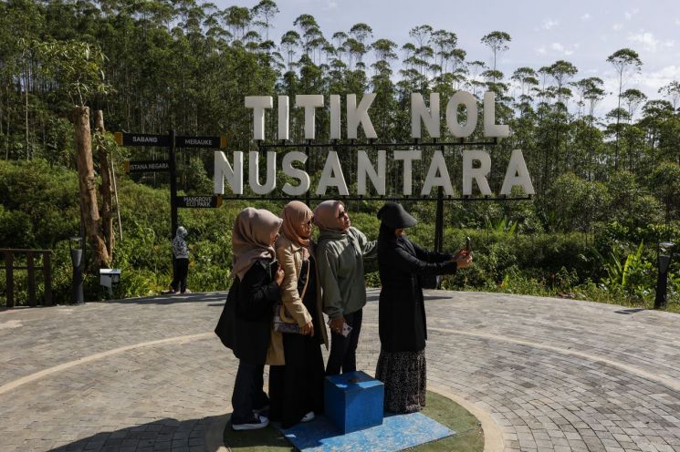 인도네시아 여성들이 새 수도인 누산타라 건설 현장의 이정표 앞에서 기념 사진을 찍고 있다. [이미지출처=EPA연합뉴스]