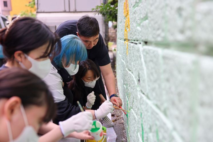 경남정보대 학생들이 사상구 괘내마을의 노후 옹벽 약 50ｍ에 벽화를 그리고 있다.