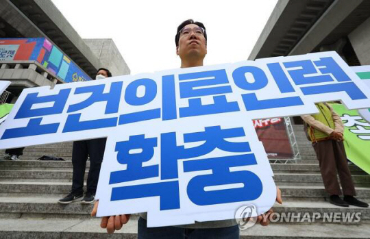 지난 7일 서울 세종문화회관 앞에서 열린 보건의료노조 서울지역본부 투쟁선포 기자회견에서 한 참가자가 구호가 적힌 피켓을 들고 있다. [사진출처=연합뉴스]