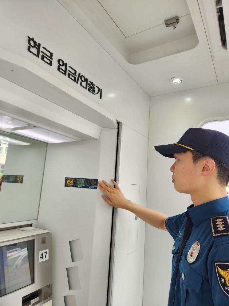 경찰이 현금 입출금기 옆면에 국민체감 약속 자석 스티커를 붙이고 있다. [사진제공=경남경찰청]