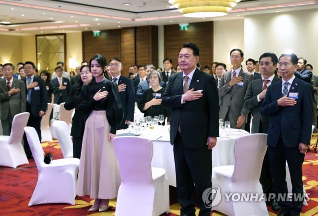 폴란드를 공식 방문한 윤석열 대통령과 김건희 여사가 12일(현지시간) 바르샤바 한 호텔에서 열린 동포간담회에서 국기에 경례하고 있다.[사진출처=연합뉴스]