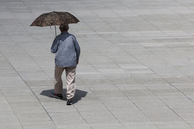 지난 26일 오후 서울 광화문광장에서 한 시민이 양산으로 햇볕을 가리며 이동하고 있다. [이미지출처=연합뉴스]