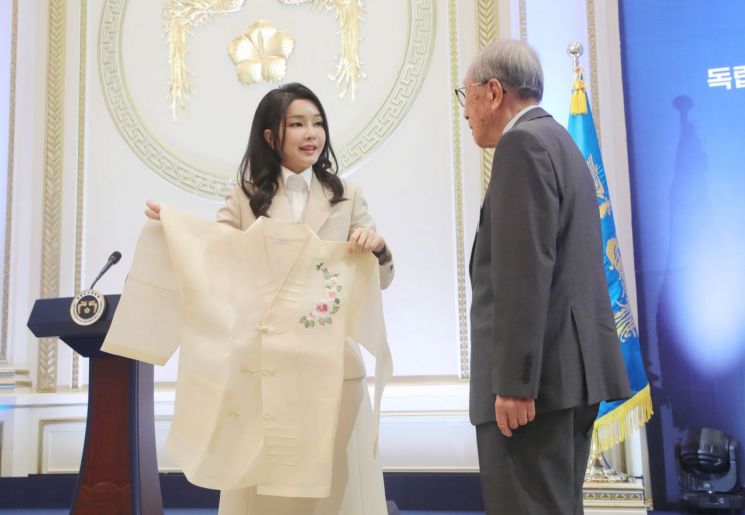 윤석열 대통령 부인 김건희 여사가 9일 청와대 영빈관에서 열린 독립유공자 및 유족 초청 오찬에서 김영관 애국지사에게 무궁화 자수 한산모시 적삼을 선물하고 있다. [이미지출처=연합뉴스]