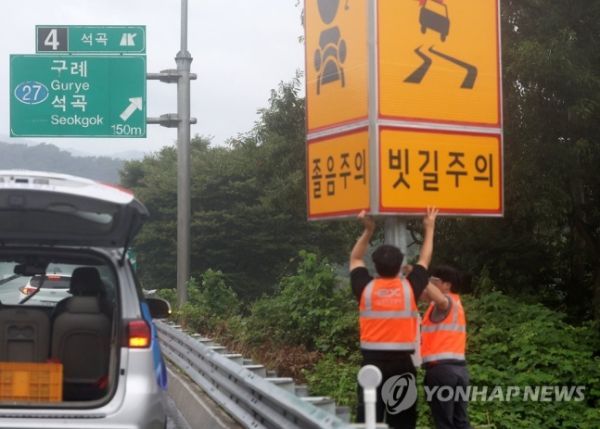 태풍 카눈이 북상 중인 9일 오후 한국도로공사 순천지사 직원들이 호남고속도로 천안방면 주의표지판 방향을 졸음주의에서 빗길주의로 돌리고 있다. [사진제공=연합뉴스]