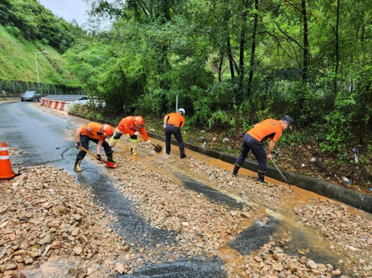 경남 창원시 성산구 상복나들목(IC) 인근 도로에 낙석이 쏟아져 소방대원들이 도로를 정리하고 있다. [사진제공=창원소방본부]