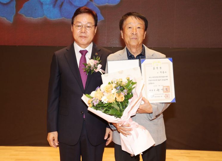 박완수 경남도지사(왼쪽)가 독립유공자 고 박점수 선생의 자녀 박재형 씨에게 대통령 표창을 건네고 기념촬영을 하고 있다. [사진제공=경남도청]