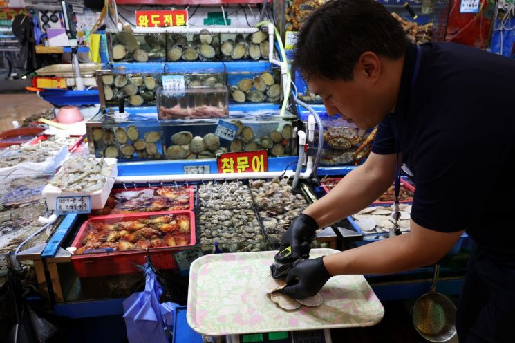 후쿠시마 제1원자력발전소 오염수의 해양 방류를 하루 앞둔 23일 오후 서울 동작구 노량진수산시장에서 시장관리부 직원이 일본산 수산물에 대해 방사능 검사를 하고 있다. [이미지출처=연합뉴스]