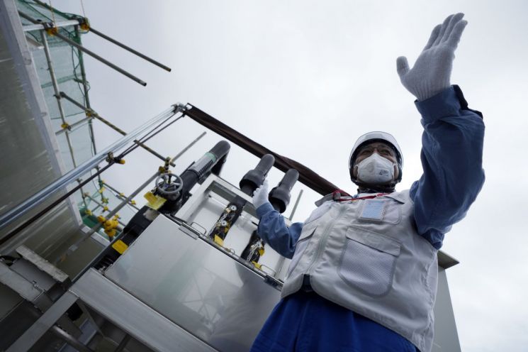 도쿄전력 관계자가 27일 일본 후쿠시마현 후타마에 있는 후쿠시마 제1원자력발전소에서 희석을 완료한 오염수(일본 정부 명칭 '처리수')의 샘플을 채취하는 기계를 기자들에게 설명하고 있다. [이미지출처=AP연합뉴스]