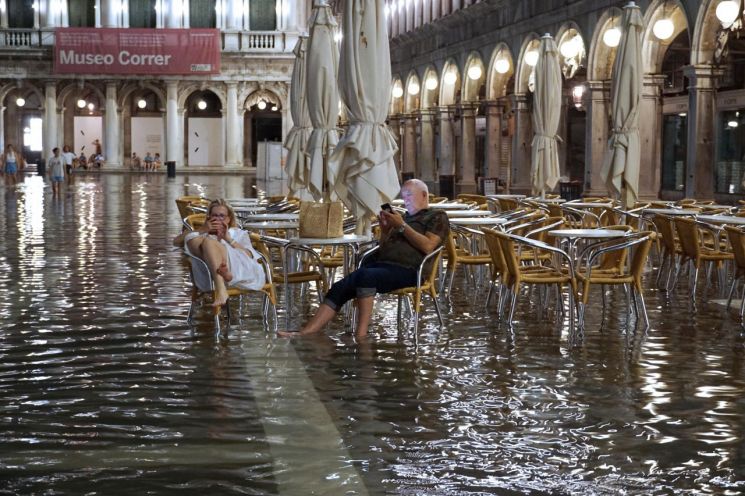 지난 8월 2일(현지시간) 심야에 사람들이 해수면 상승으로 물에 잠긴 이탈리아 북부 베네치아의 산마르코 광장에 앉아 있다 [사진출처=EPA·연합뉴스]