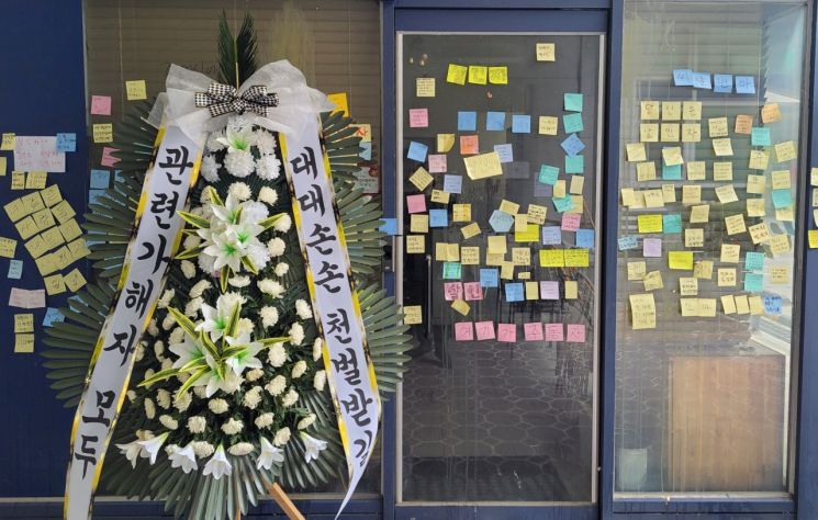 지난 9월12일 사망한 대전 초등학교 교사의 가해자로 지목된  학부모가 운영 중인 가게 앞에 해당 학부모를 비판하는 내용의 근조화환과 함께 메모가 붙어 있다.[사진출처=연합뉴스]